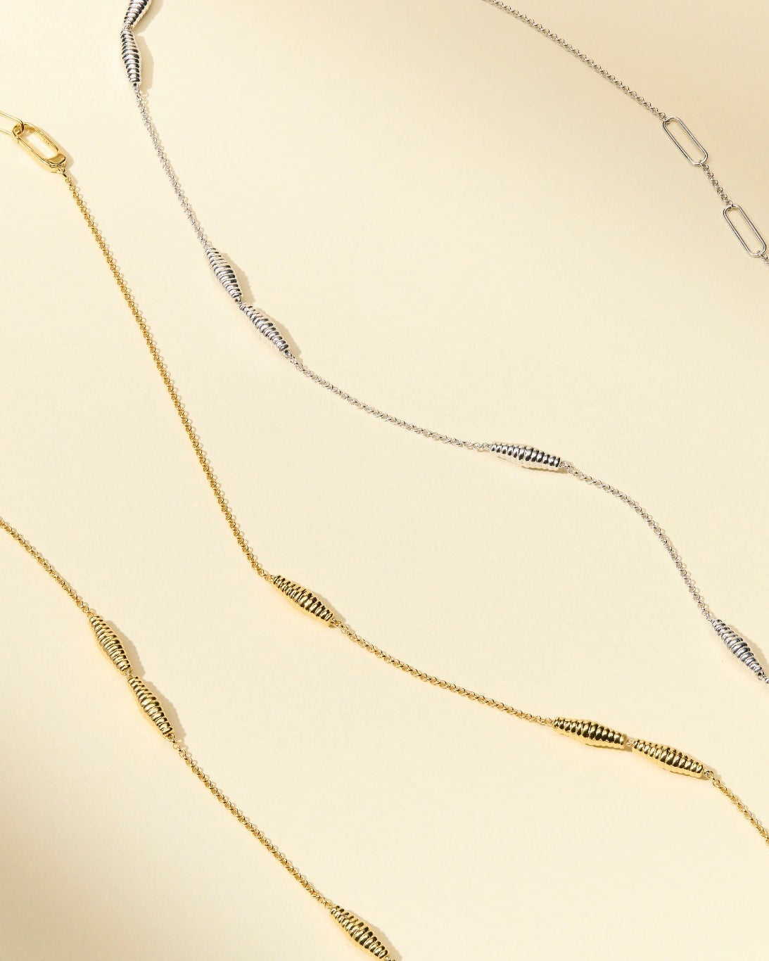 Two gold necklaces on a beige background